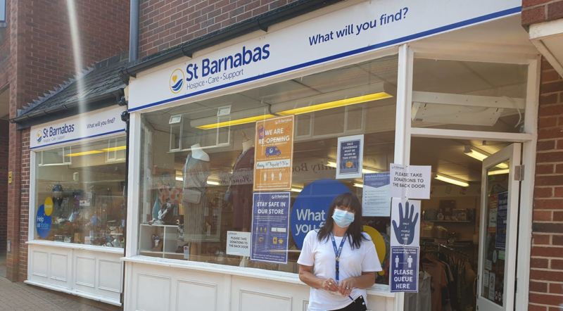A woman wearing a blue Covid-19 face mask in front of the St Barnabas Hospice charity shop in Grantham