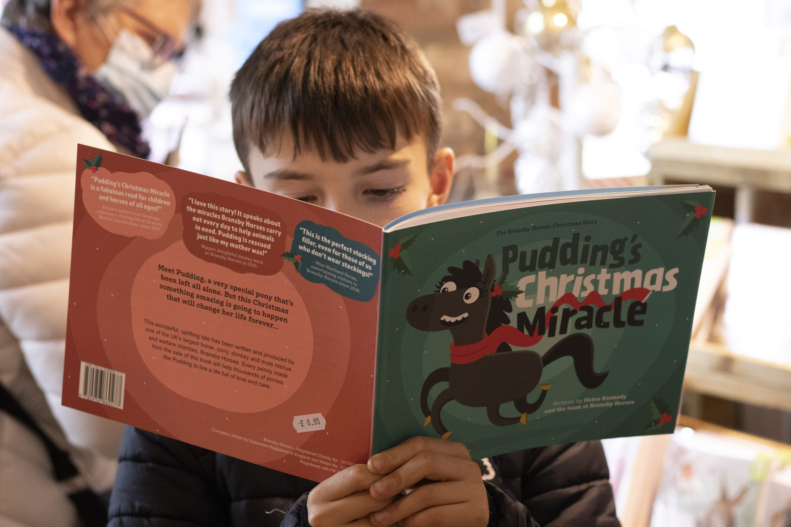 Young child reading a book - Pudding's Christmas Miracle, written to help raise funds for equine charity Bransby Horses