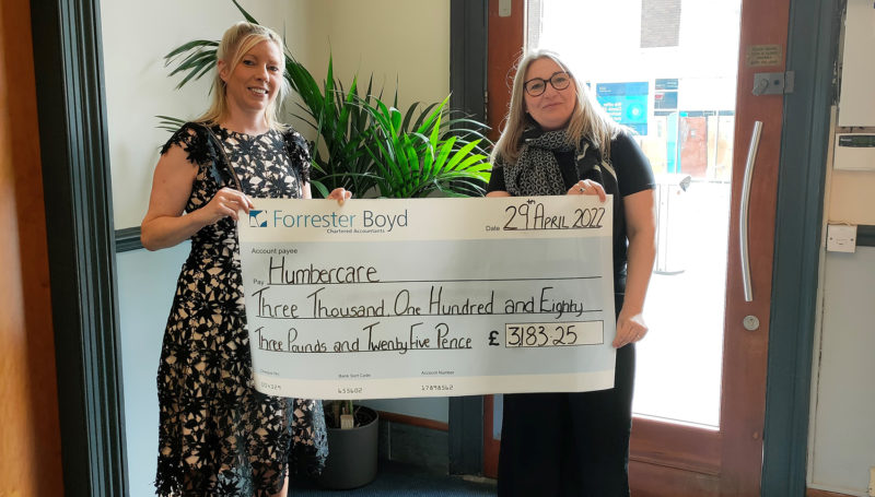 Two blonde women holding a Forrester Boyd cheque for £3,183.25 to Humbercare Charity.